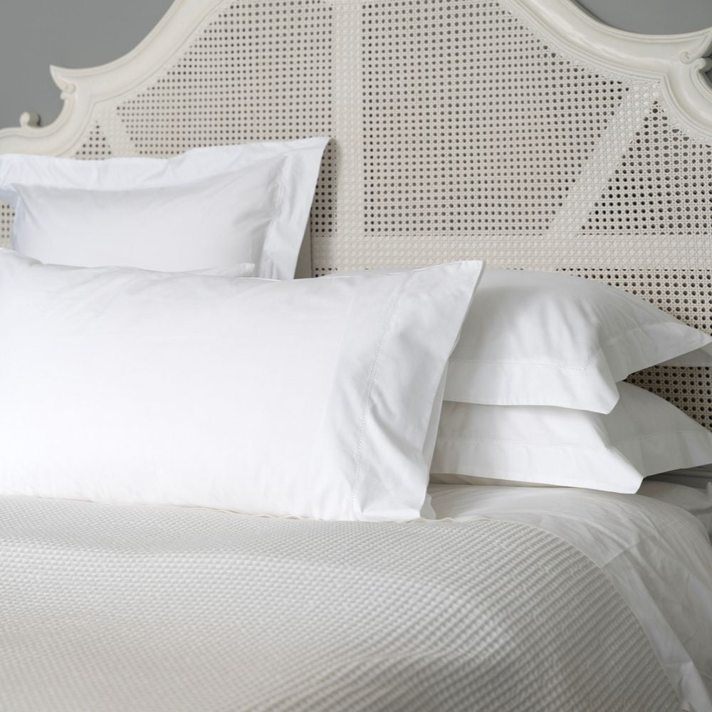 White pillows on a bed with a textured headboard