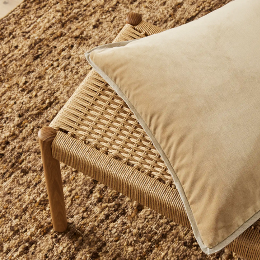 Francesca cushion on a woven stool with a roughly textured carpet