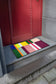 Colorful doormat with geometric pattern on a concrete step leading to a red door.