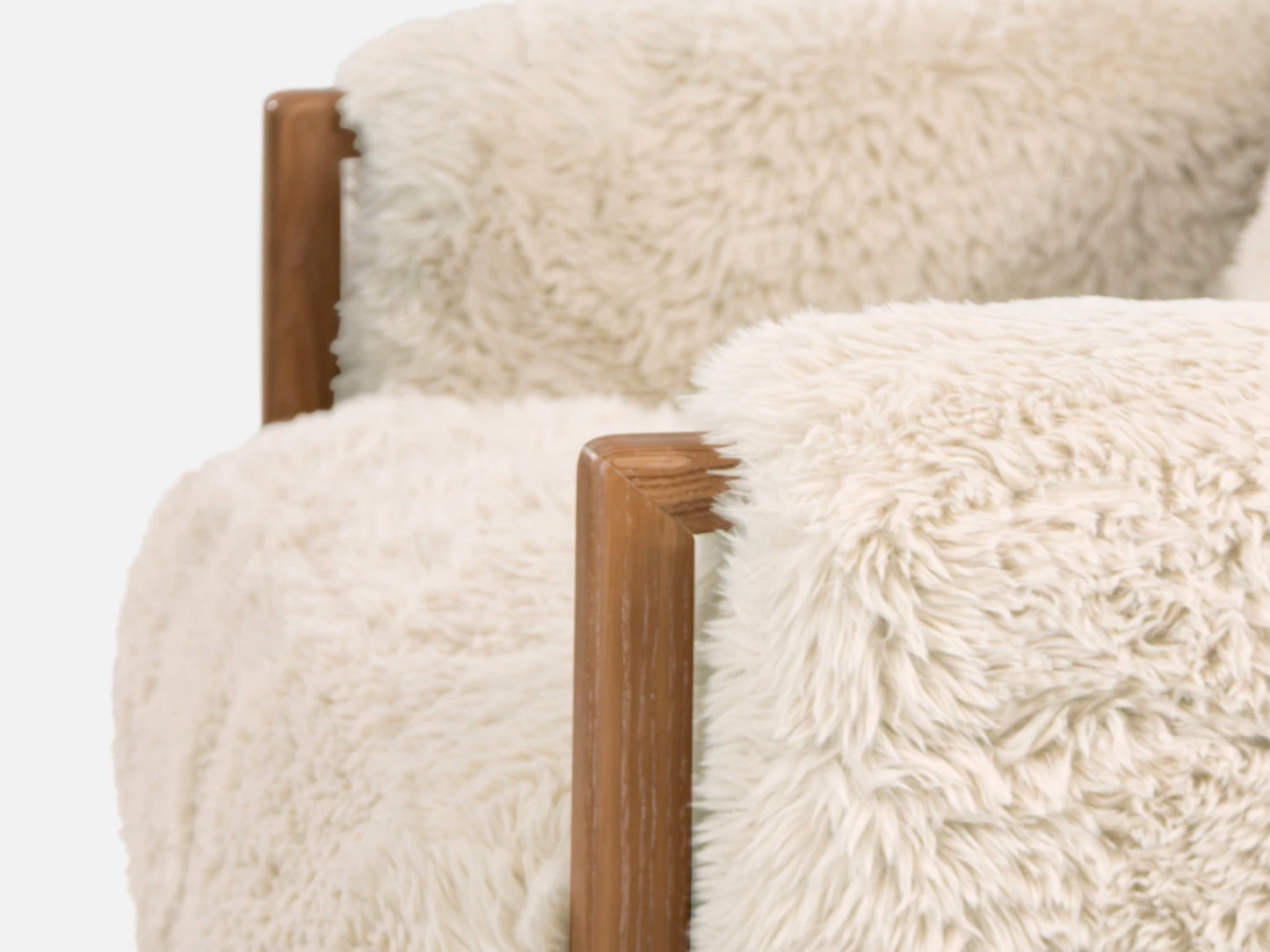 Close-up of a chair with white fluffy cushions and wooden armrests on a white background