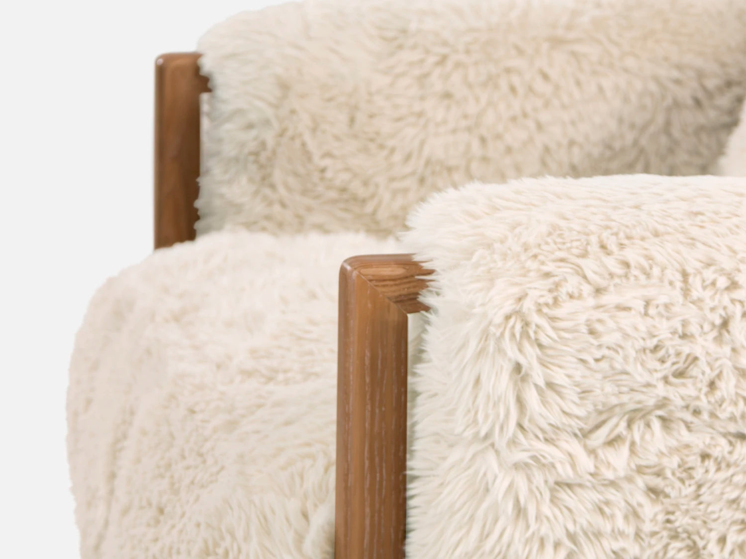 Close-up of a chair with white fluffy cushions and wooden armrests on a white background