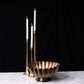 Brass candle holder with three white candles on a dark background