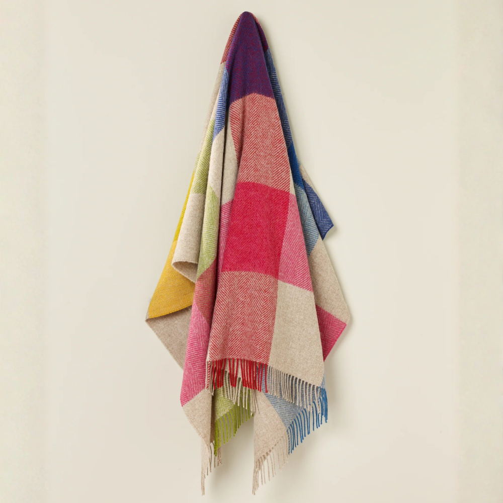 Colorful plaid blanket draped over a chair against a beige wall