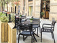 Outdoor seating area with black chairs and tables on a city street.