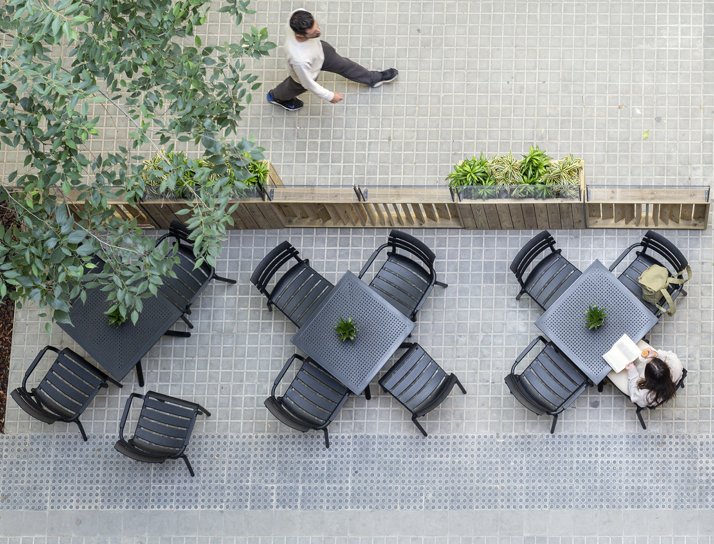 Top-down view of an outdoor seating area with tables and chairs on a tiled patio.