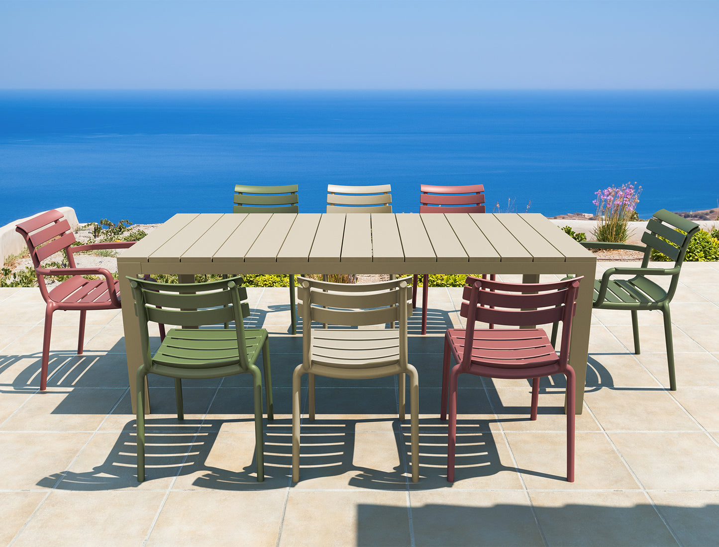Outdoor dining set with colorful chairs around a wooden table by the ocean.
