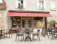 Outdoor seating area in front of a store with tables, chairs, and a red awning.