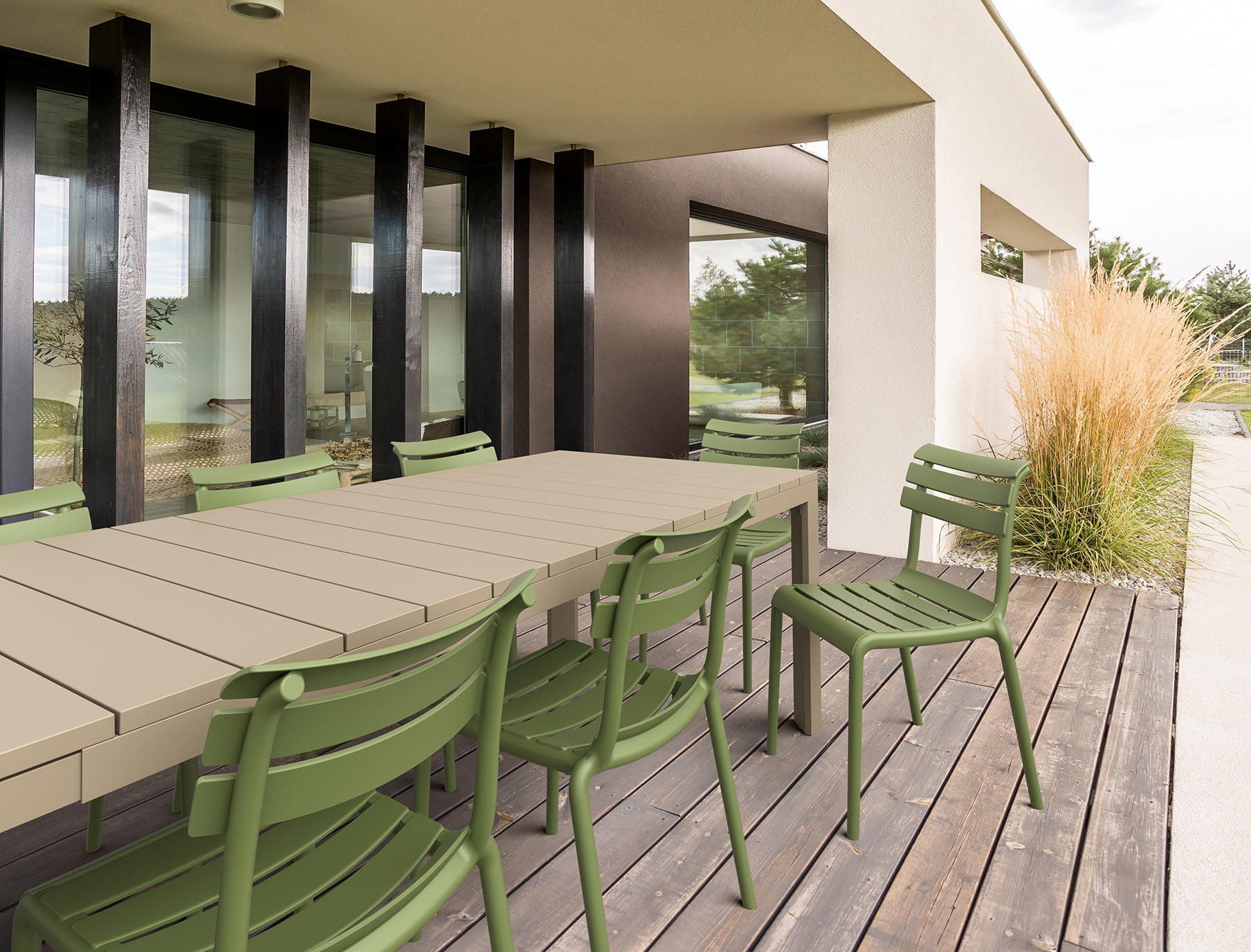 Outdoor setting with a long wooden table and green chairs on a deck.