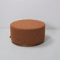 Round brown fabric ottoman on a light gray background
