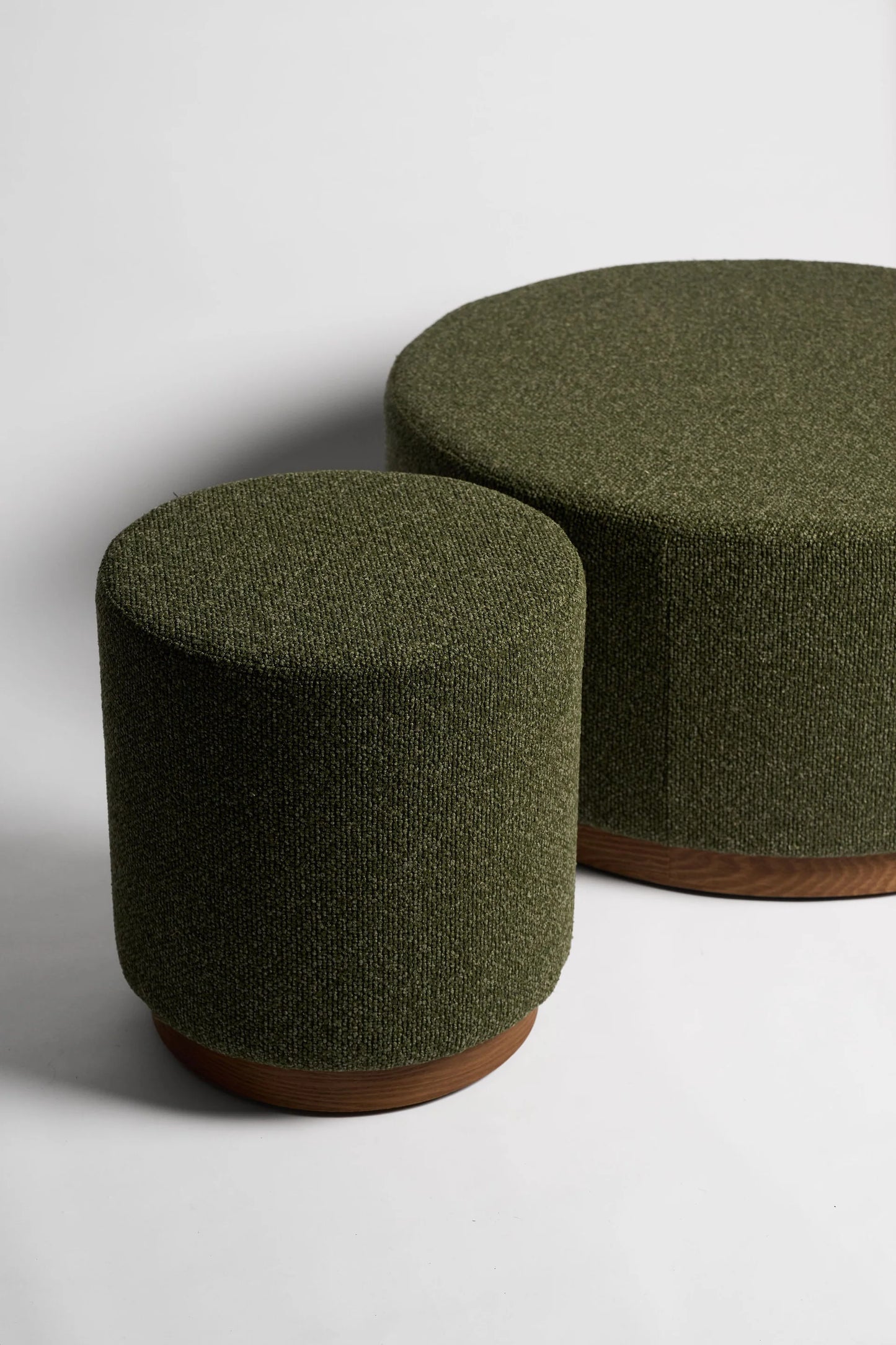 Two green cylindrical ottomans on a white background