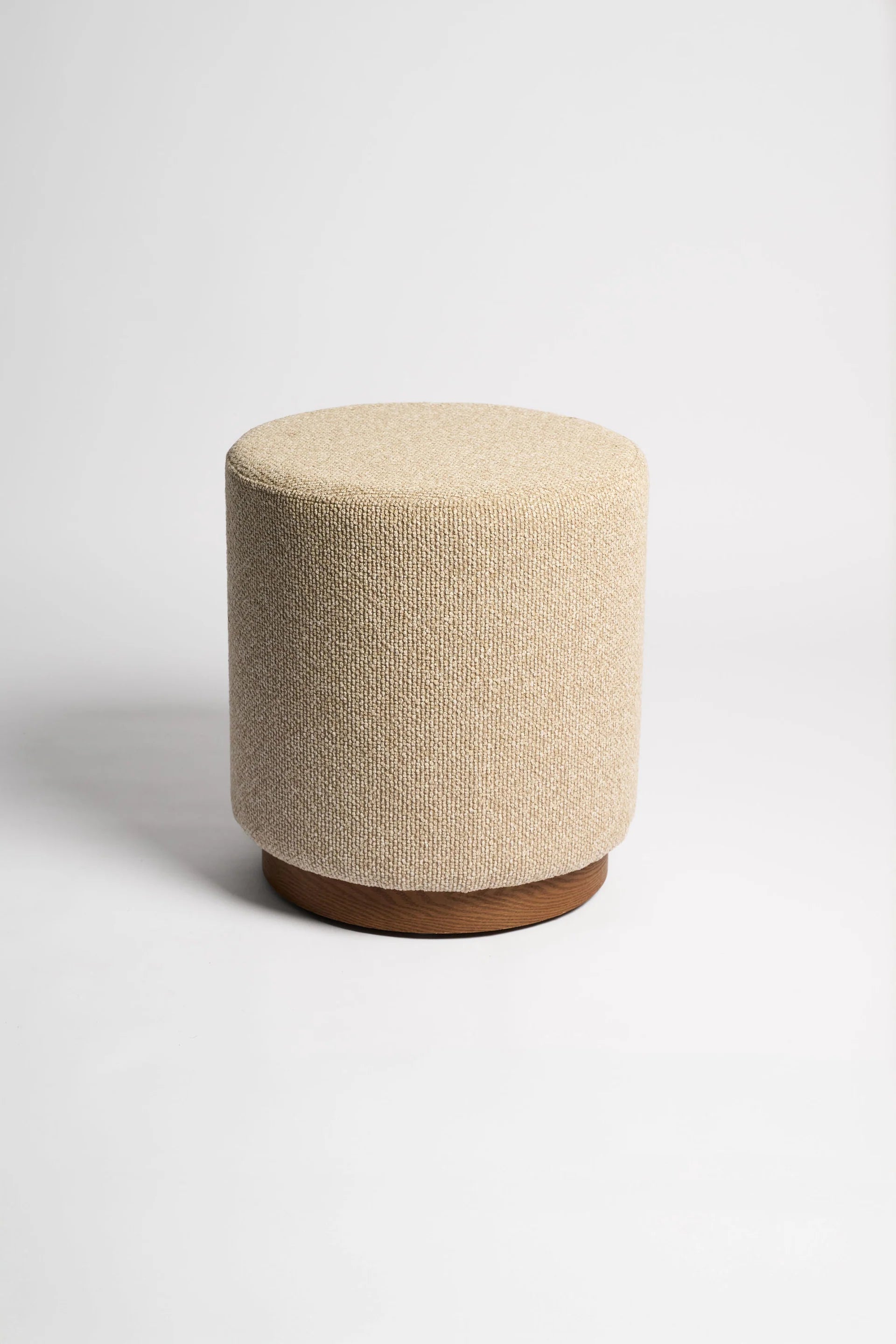 Beige textured ottoman with a wooden base on a white background
