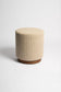 Beige textured ottoman with a wooden base on a white background