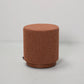 Brown textured cylindrical stool on a light gray background