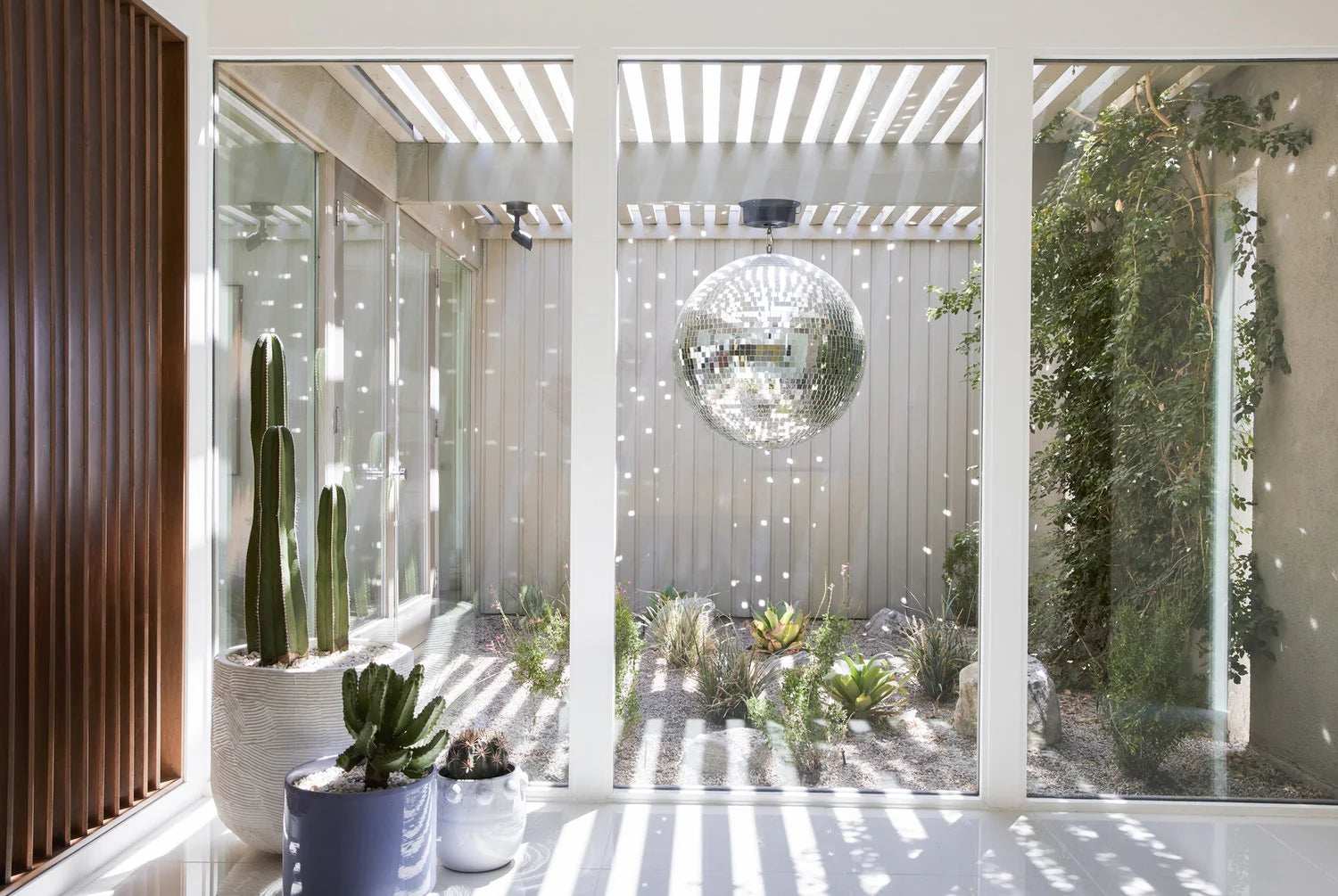 Modern interior with glass walls, plants, and a decorative mirror.