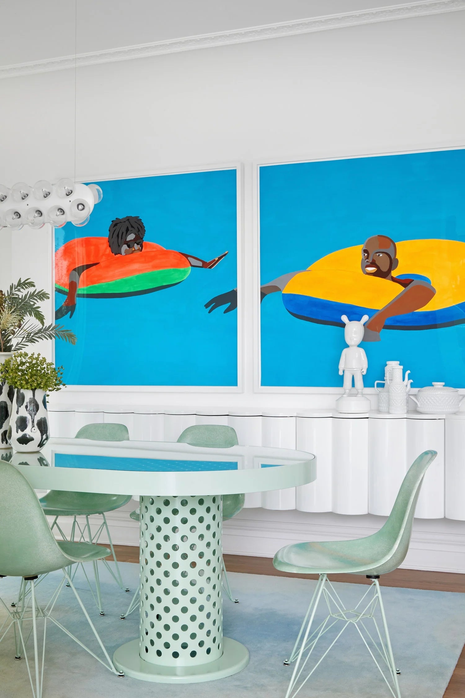 Dining room with a table and chairs, featuring two large abstract paintings on the wall.