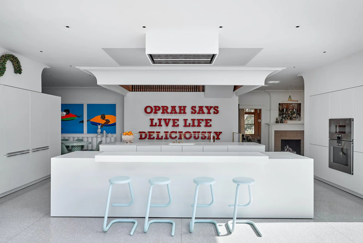 Modern kitchen with a quote on the wall, featuring white cabinetry and a central island.