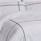 White bedding set with black piping on a plain background