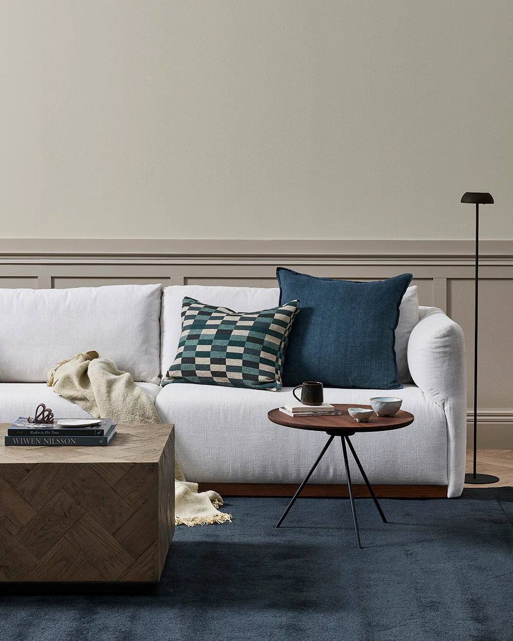 Modern living room with a white sofa, decorative pillows, and a wooden coffee table.