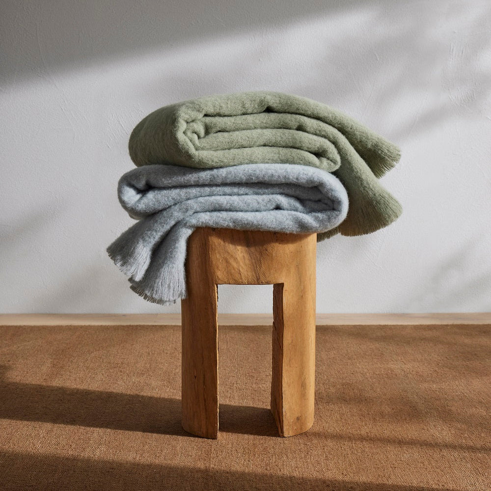 2 throws in green and blue on a wooden stool