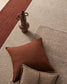 Brown pillow and decorative vase on a textured beige and red rug
