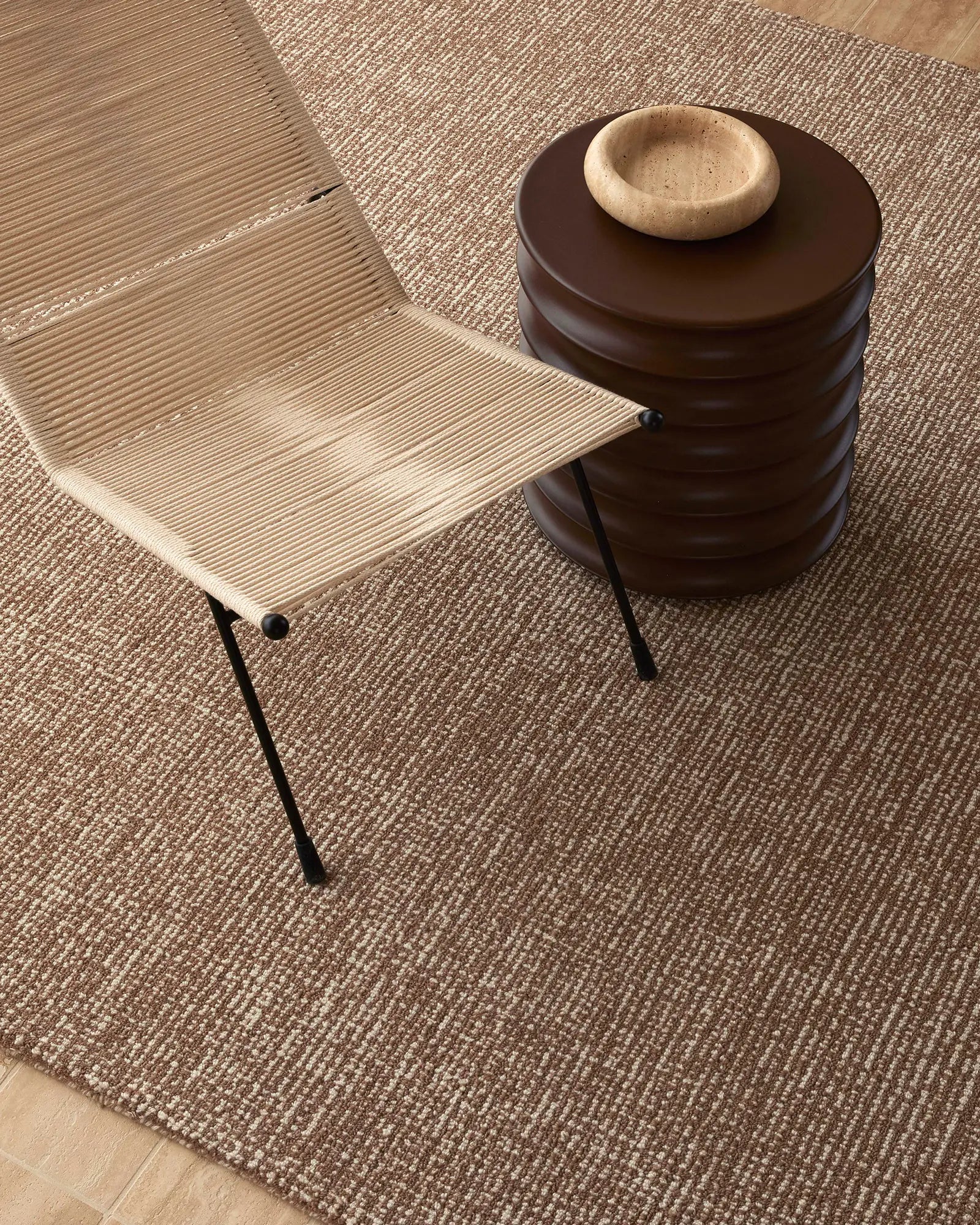 Beige chair and brown ottoman on a textured brown floor