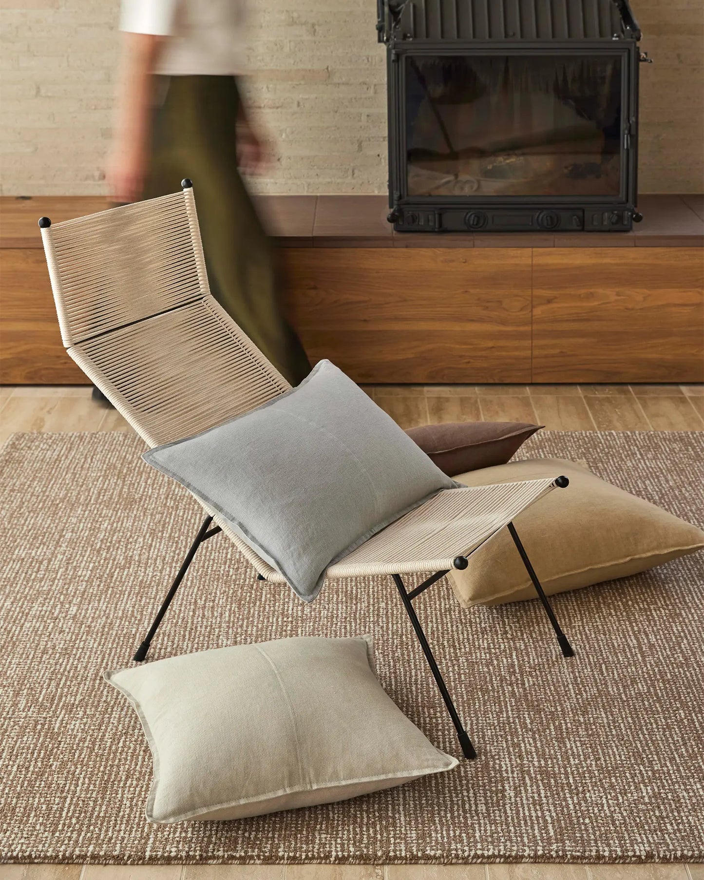 Foldable chair with cushions on a rug in a room with wooden furniture.