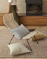 Foldable chair with cushions on a rug in a room with wooden furniture.