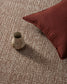 Ceramic vase and red pillow on a textured carpet