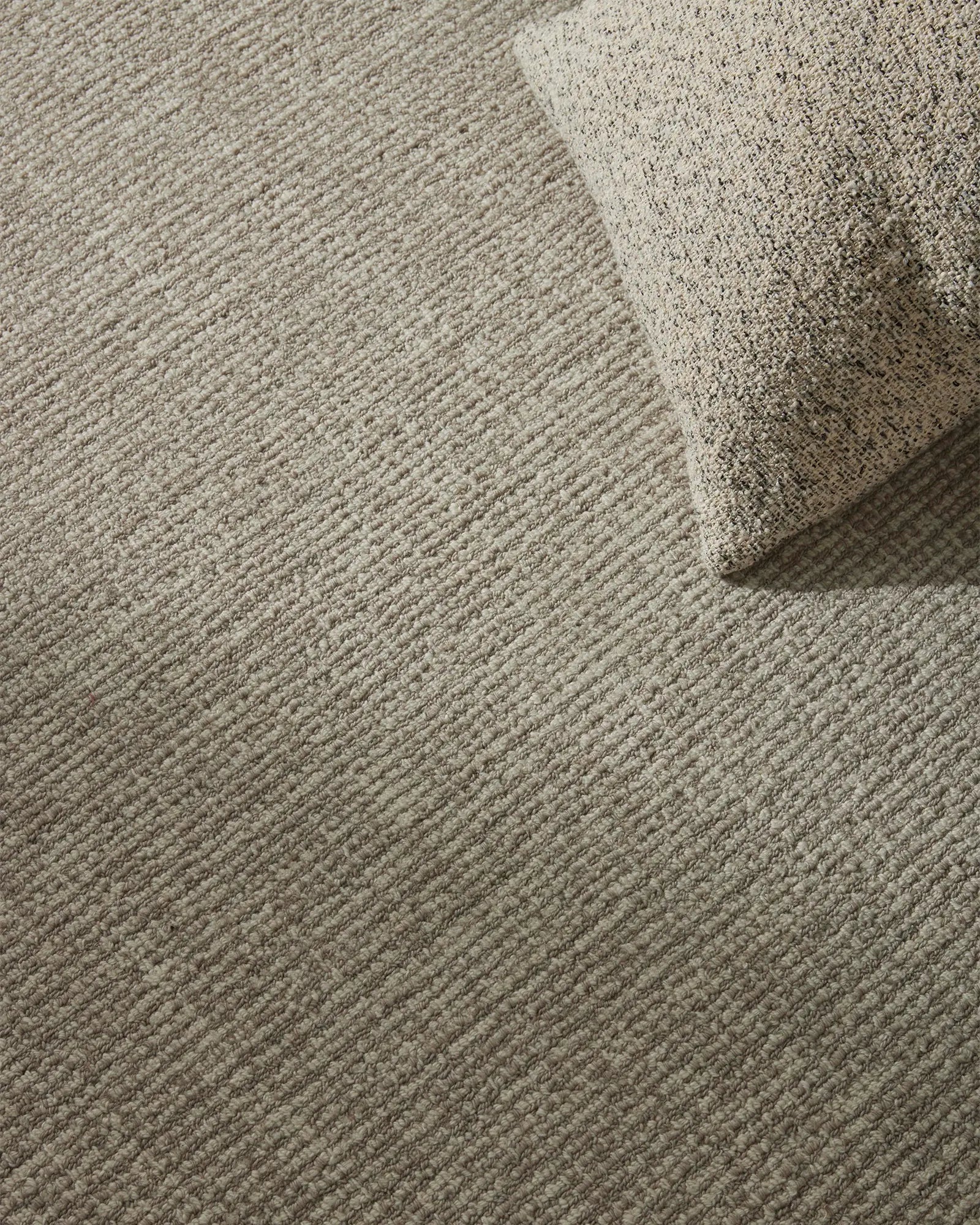 Close-up of a textured beige carpet with a folded corner.