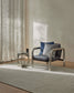 Modern chair with blue and gray cushions in a room with curtains and a rug.