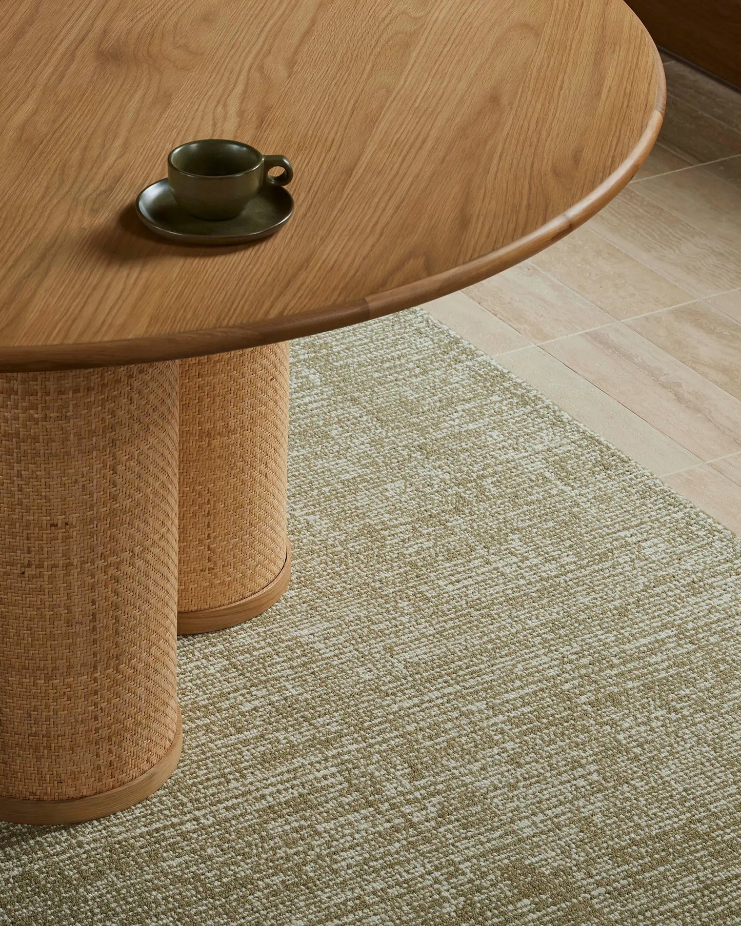 Round wooden table with a cup on a textured green carpet