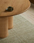Round wooden table with a cup on a textured green carpet