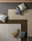 Colorful pillows on a textured rug with geometric pattern