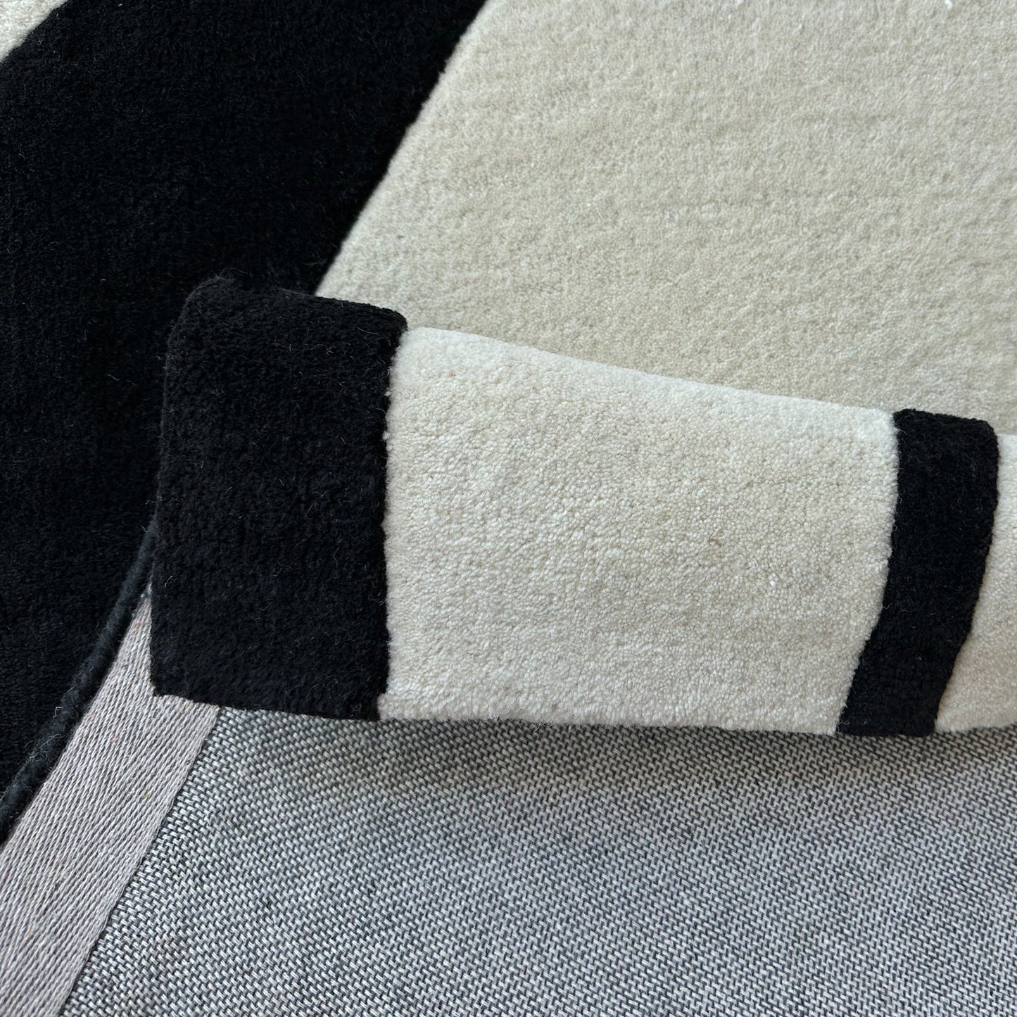 Close-up of a textured rug with black and white stripes on a neutral background