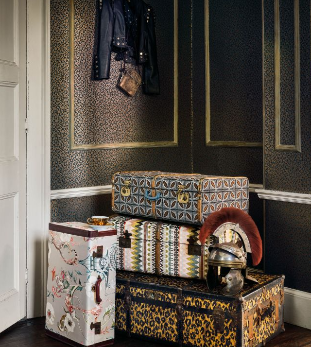 Decorative trunks stacked against a dark paneled wall with a white baseboard.