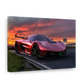A rectangular wall art print or canvas showing a glossy red supercar on a road at sunset, photographed against a plain white background.