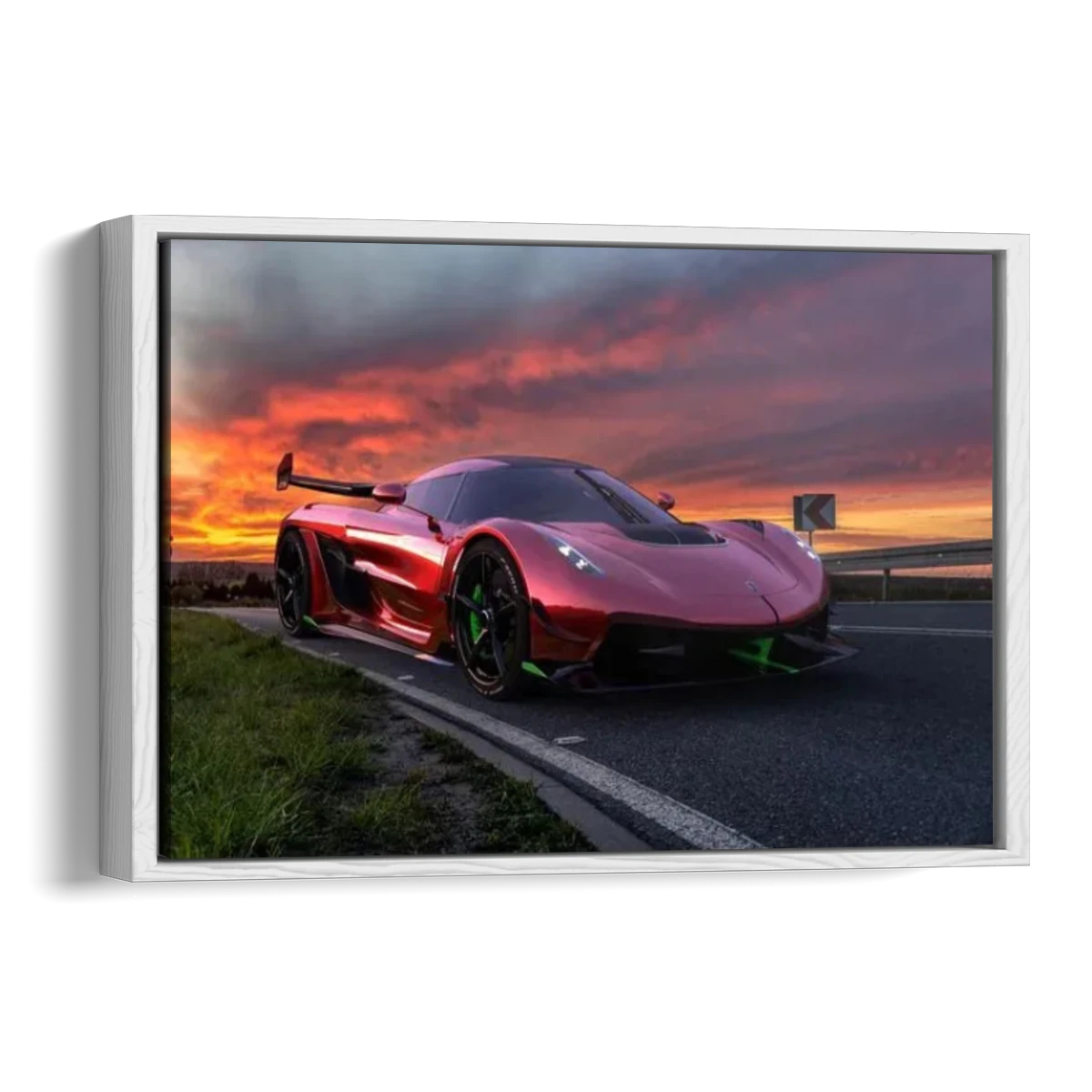 A framed wall art print showing a red supercar on a road at sunset, displayed against a plain white background.
