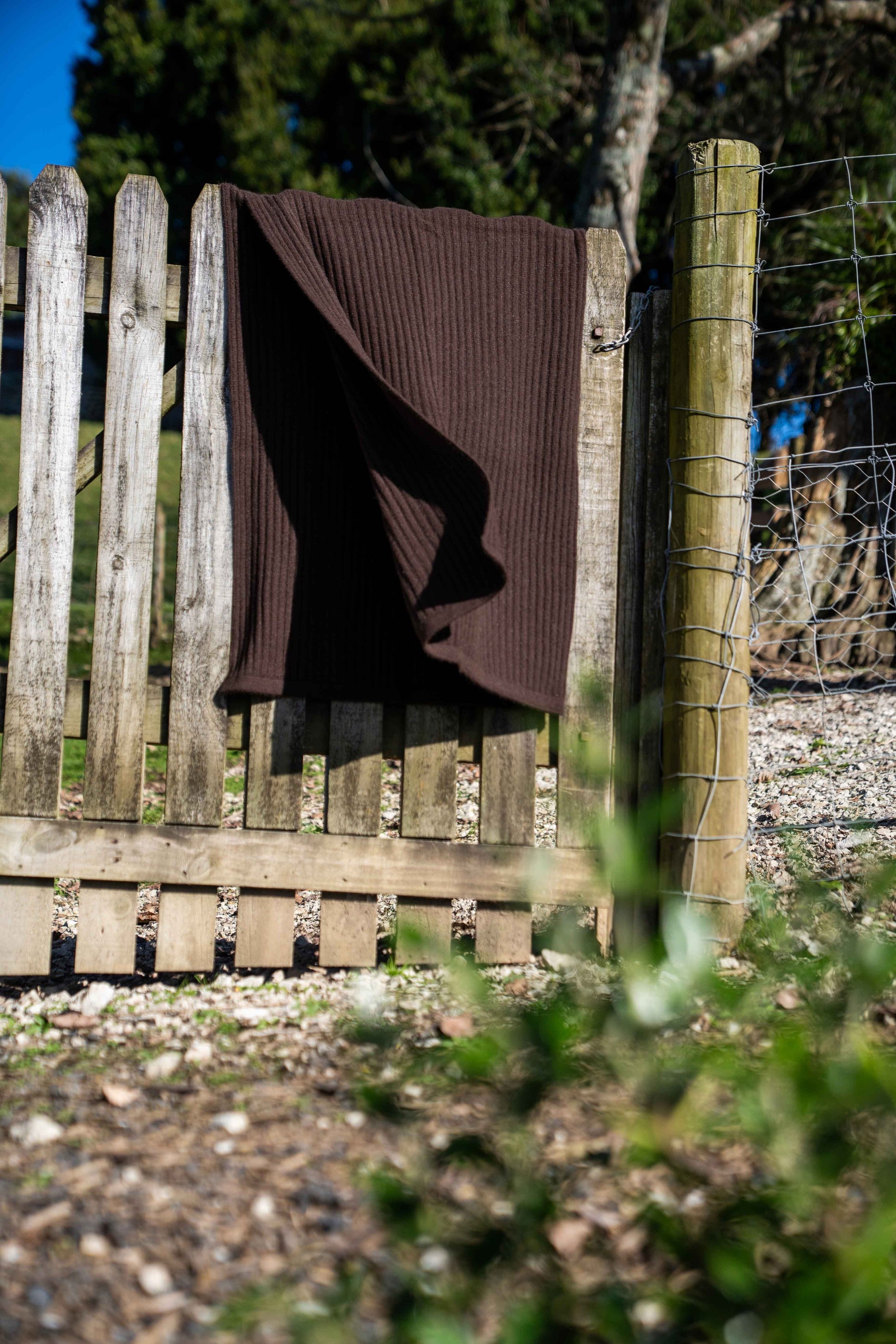 chocolate brown throw over a wooden fence in an outdoor setting