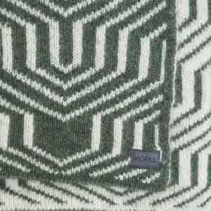 A patterned throw with geometric design draped over a blue upholstered chair with wooden legs.