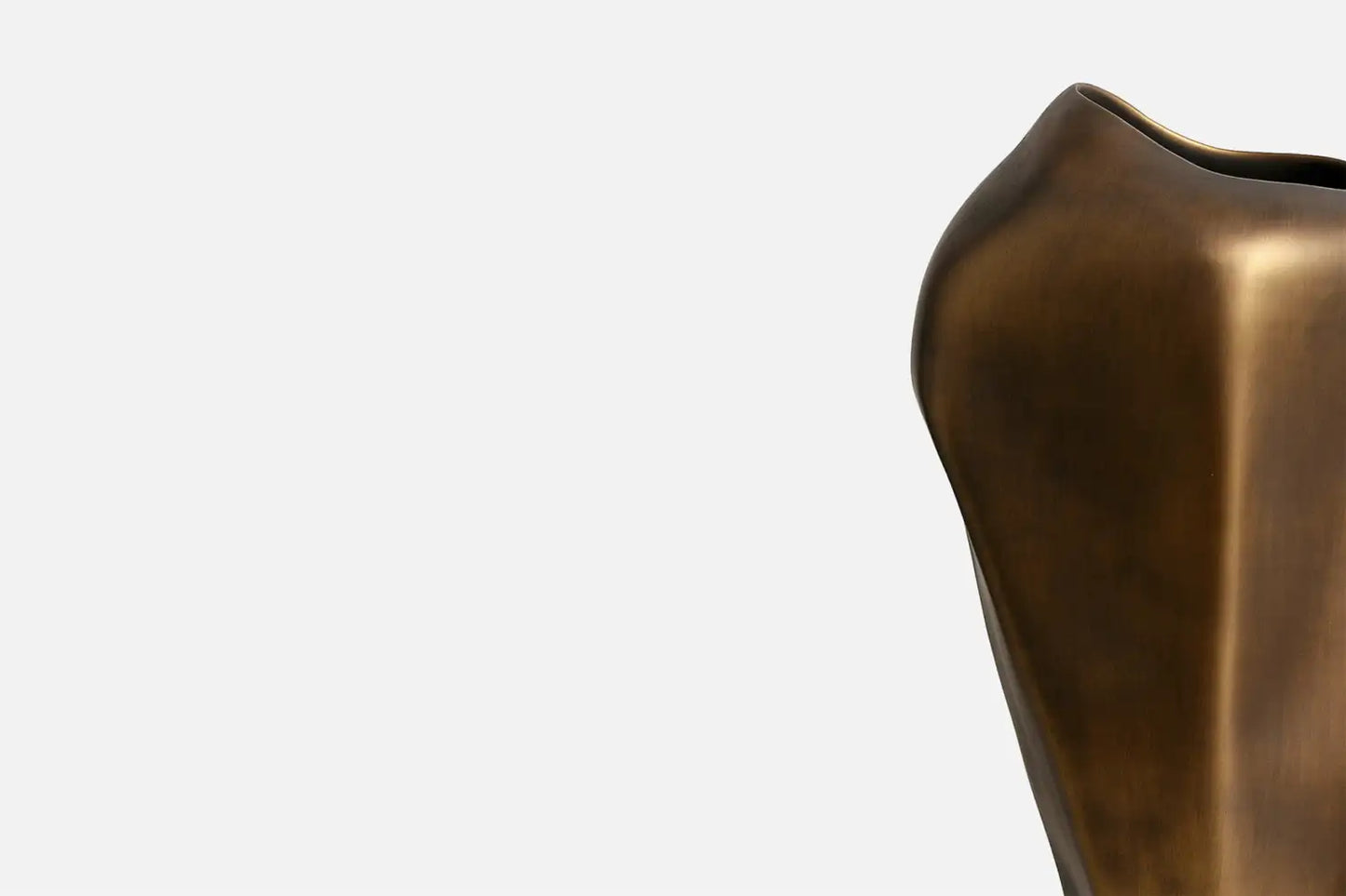 Close-up of a sculptural vase in a brushed bronze finish, positioned on the right side of a clean white background.