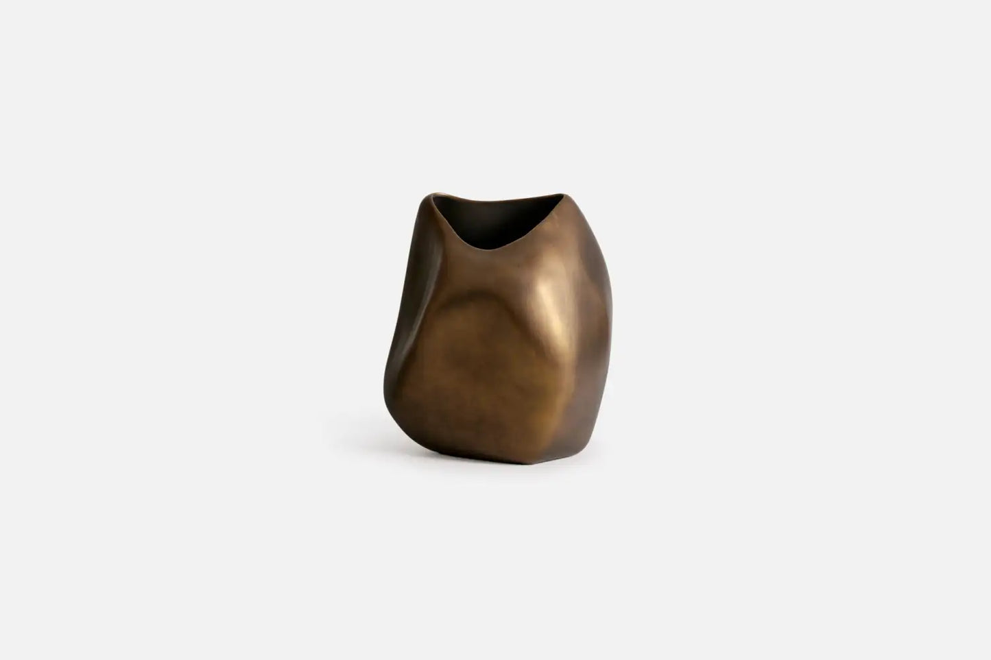 A modern, abstract sculptural ceramic vase with a metallic bronze finish, set against a plain light gray background.