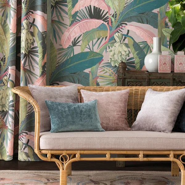 Decorative interior with a wicker sofa, colorful pillows, and tropical-themed wallpaper.