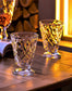 Two clear cut-crystal goblets with a diamond pattern, displayed on a rustic wooden table with warm ambient lighting.