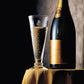 Bottle of champagne and a glass with bubbles on a dark background