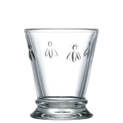 Clear glass tumbler with bee embossing on a white background