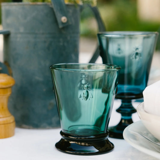 Teal glass with black base on a table with blurred background