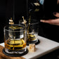 Two glasses with ice cubes and a ship design, one being filled with liquid on a dark background.