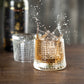 Glass with liquid splashing out, blurred bottle in the background