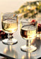 Two wine glasses filled with white wine on a reflective surface with blurred background