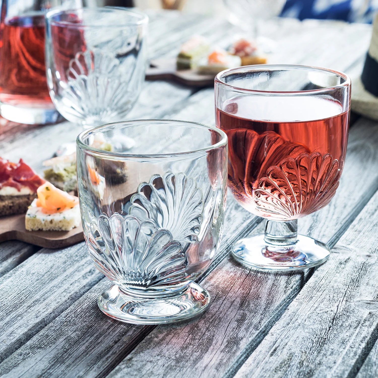 Two glasses of red wine on a wooden table with appetizers
